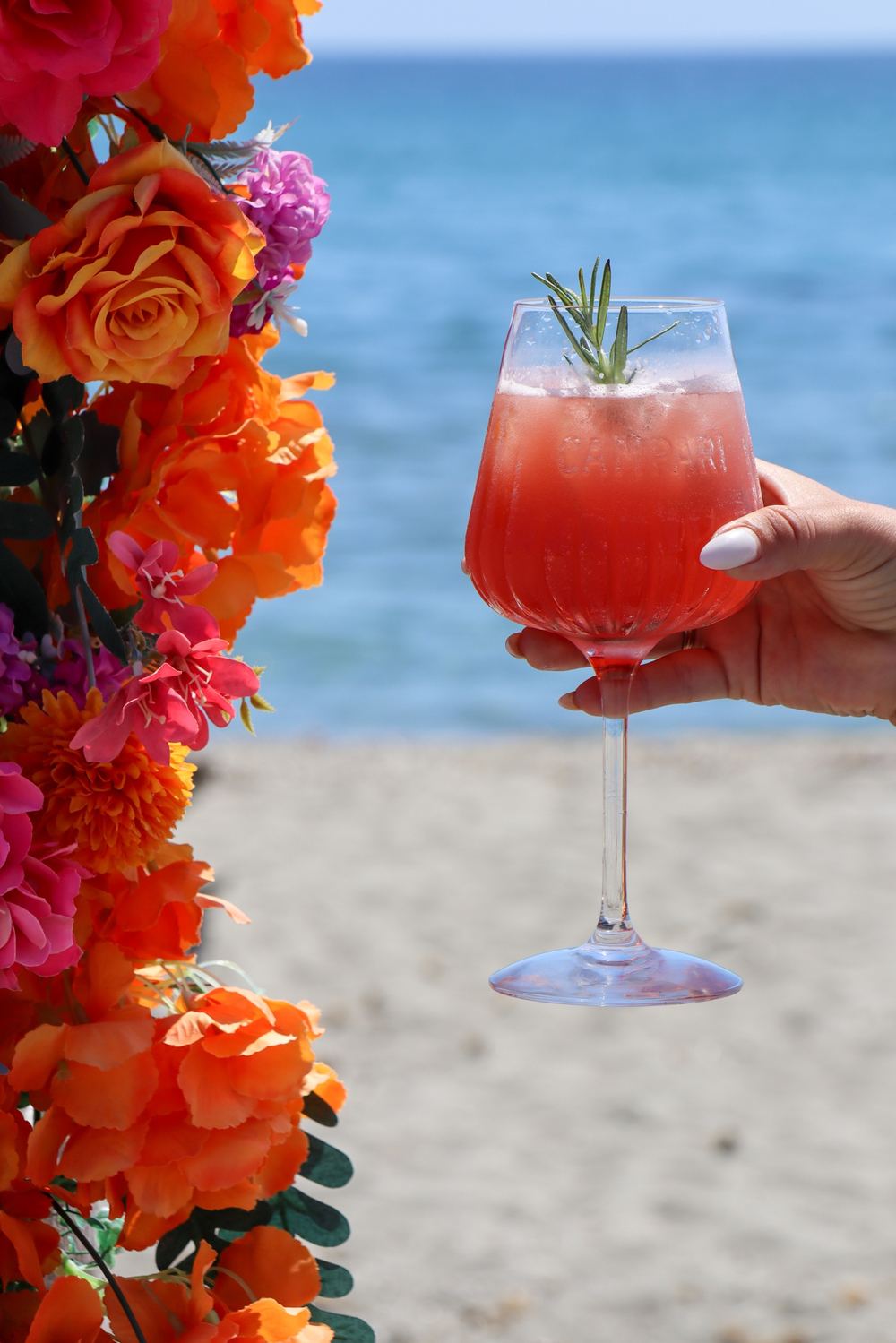 Cocktail tenu devant une arche de fleurs orange, face à la mer